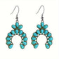 Pair of antique silver tone crescent drop earrings with turquoise colored stones hanging from fish hook ear wires