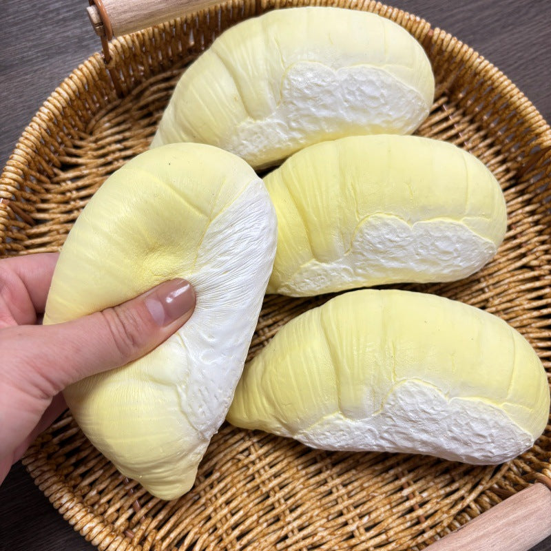 Three matte creamy durian squishy segments lying in a rattan tray, sculpted husk texture