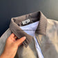 Close-up of the ribbed turn-down collar and inner label of the beige tie-dye jacket, held by hand