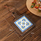 Wood trivet with a blue and yellow scrollwork tile on planks, marked 20 cm by 14 cm
