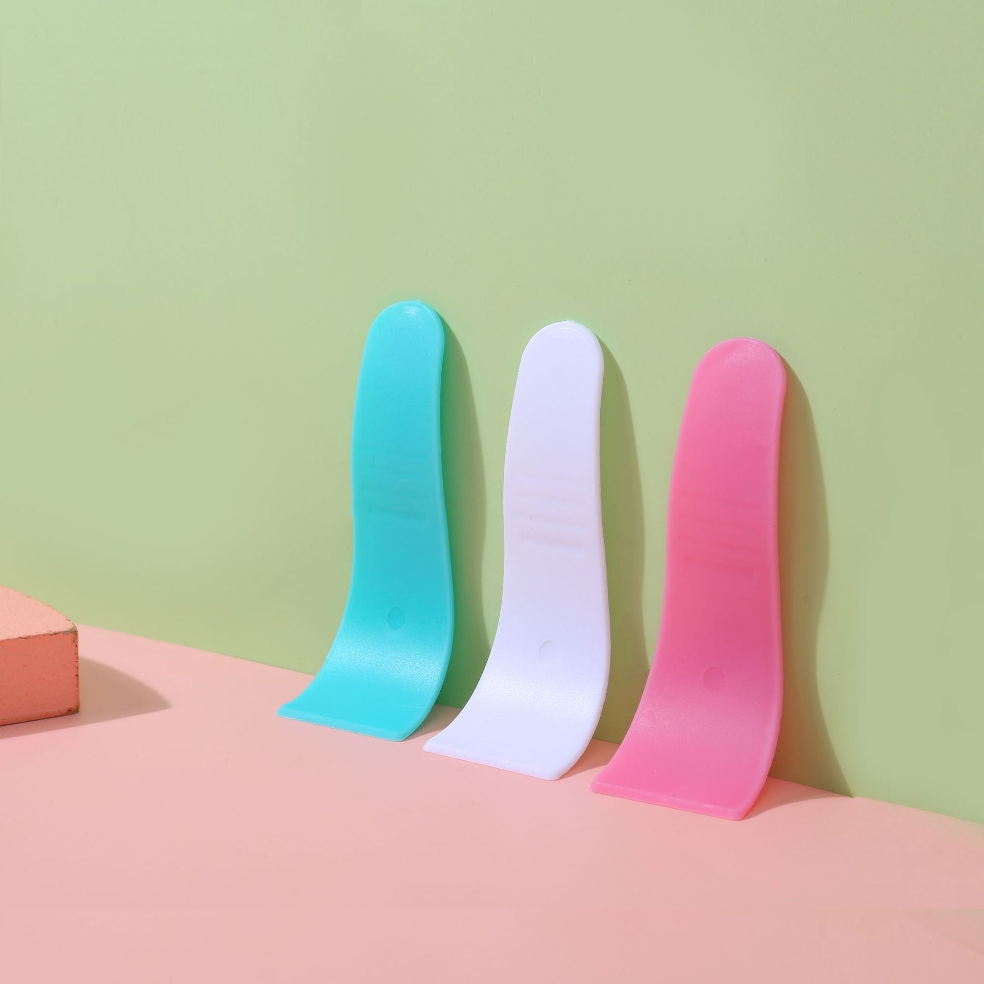 White depilatory cream scraper spatula resting on a plain studio background