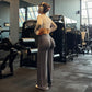 Grey high-waist flared yoga pants back view on a model in a gym, full length wide leg