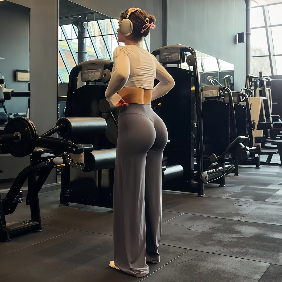 Grey high-waist flared yoga pants back view on a model in a gym, full length wide leg