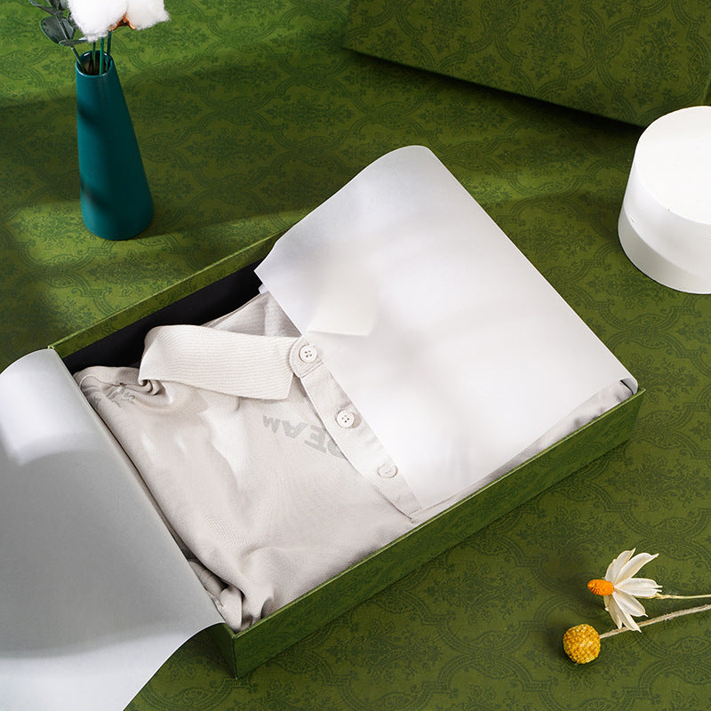Open gift box holding a folded white polo shirt, shown as an example of use