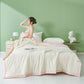 White seersucker summer cooling quilt with a colored border draped on a styled bed