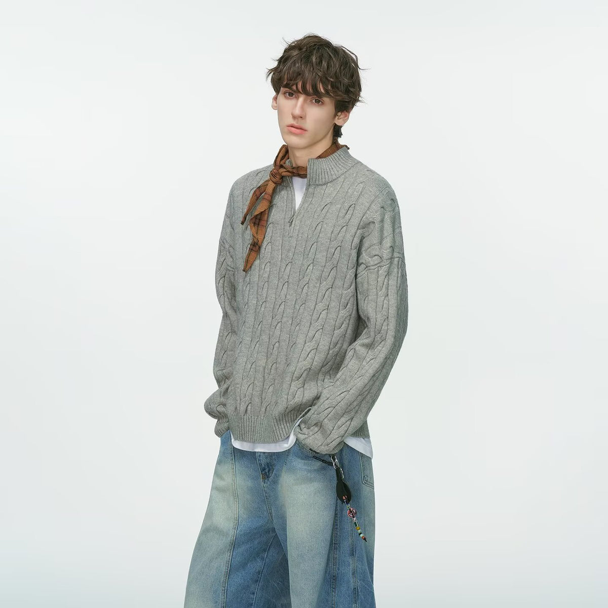 Grey half zip cable knit sweater with a plaid scarf and wide jeans on a male model, third grey option photo