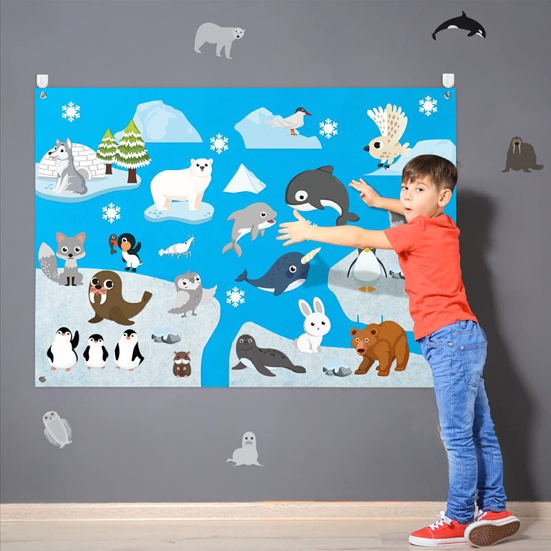 Boy adding felt polar animals to an arctic themed hanging felt story board with snow pieces