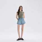 Model in light blue high waist denim shorts and a green tee, front view