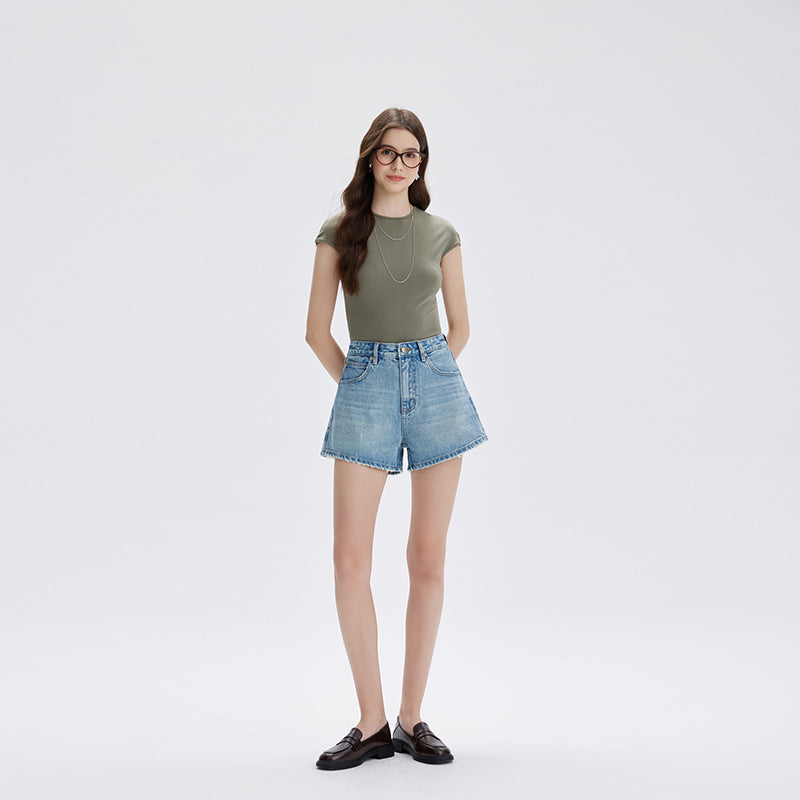 Model in light blue high waist denim shorts and a green tee, front view