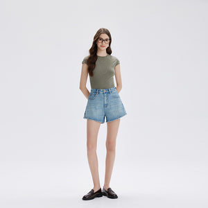 Model in light blue high waist denim shorts and a green tee, front view