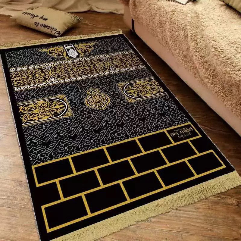Velvet Islamic prayer mat with a Kaaba wall design and gold fringe on a wood floor