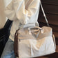 Beige and orange colorblock travel duffel worn on the shoulder with an orange strap on stairs