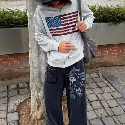 Close up of the gray flag print zip hoodie worn open with the front zipper undone over baggy jeans
