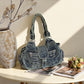 Blue washed denim shoulder bag styled on a table beside a vase and flowers