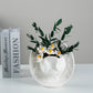 White embossed cowboy hat vase with flowers, styled beside stacked books