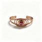 Copper cuff bracelet with faceted pink cubic zirconia and six magnets, white studio background