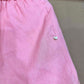 Pink linen shorts side seam with small round shell-look button near the hip