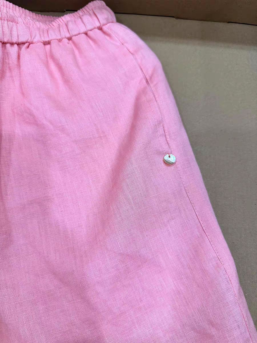 Pink linen shorts side seam with small round shell-look button near the hip