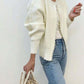 Cream faux pearl trimmed knit cardigan worn open over a white top and blue jeans