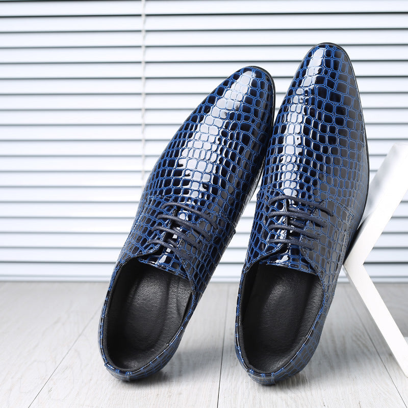 Pair of blue croc embossed derby shoes with pointed toes, black lining and laces, leaning on a white hexagon