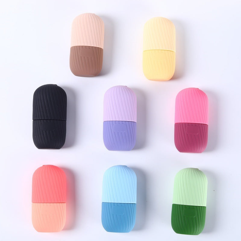 Black silicone facial ice tool laid on its side, two piece capsule join visible