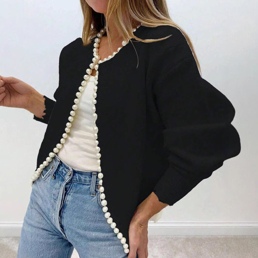 Woman wearing the black faux pearl trimmed knit cardigan open over a white top and jeans