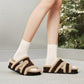 Woman seated wearing brown suede fleece trimmed open toe slippers with white socks