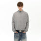 Model in a gray ribbed zip-up sweater and jeans with a belt buckle, standing against a white background
