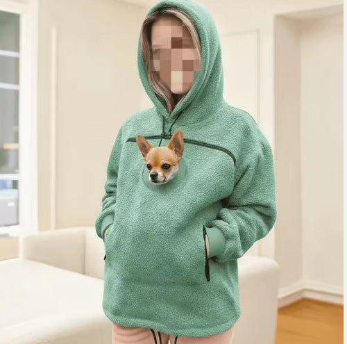 Cyan sherpa fleece pet pouch hoodie on a person with hood up and a small dog in the pouch