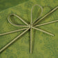 Close-up of a cord bow tied on the damask-patterned lid of an olive green gift box