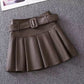 Coffee with Belt variant, size 2XL: coffee pleated mini skirt with a self-fabric belt laid flat on gray carpet