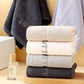 Stack of cotton hand towels in gray, white and pink with embroidered end borders