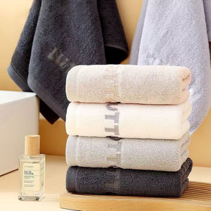 Stack of cotton hand towels in gray, white and pink with embroidered end borders