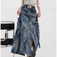 Side view of the blue acid-wash denim maxi skirt, cargo pockets and buckle straps lifting the flared hem