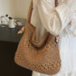 Khaki woven straw shoulder bag with colorful strap held at the side indoors