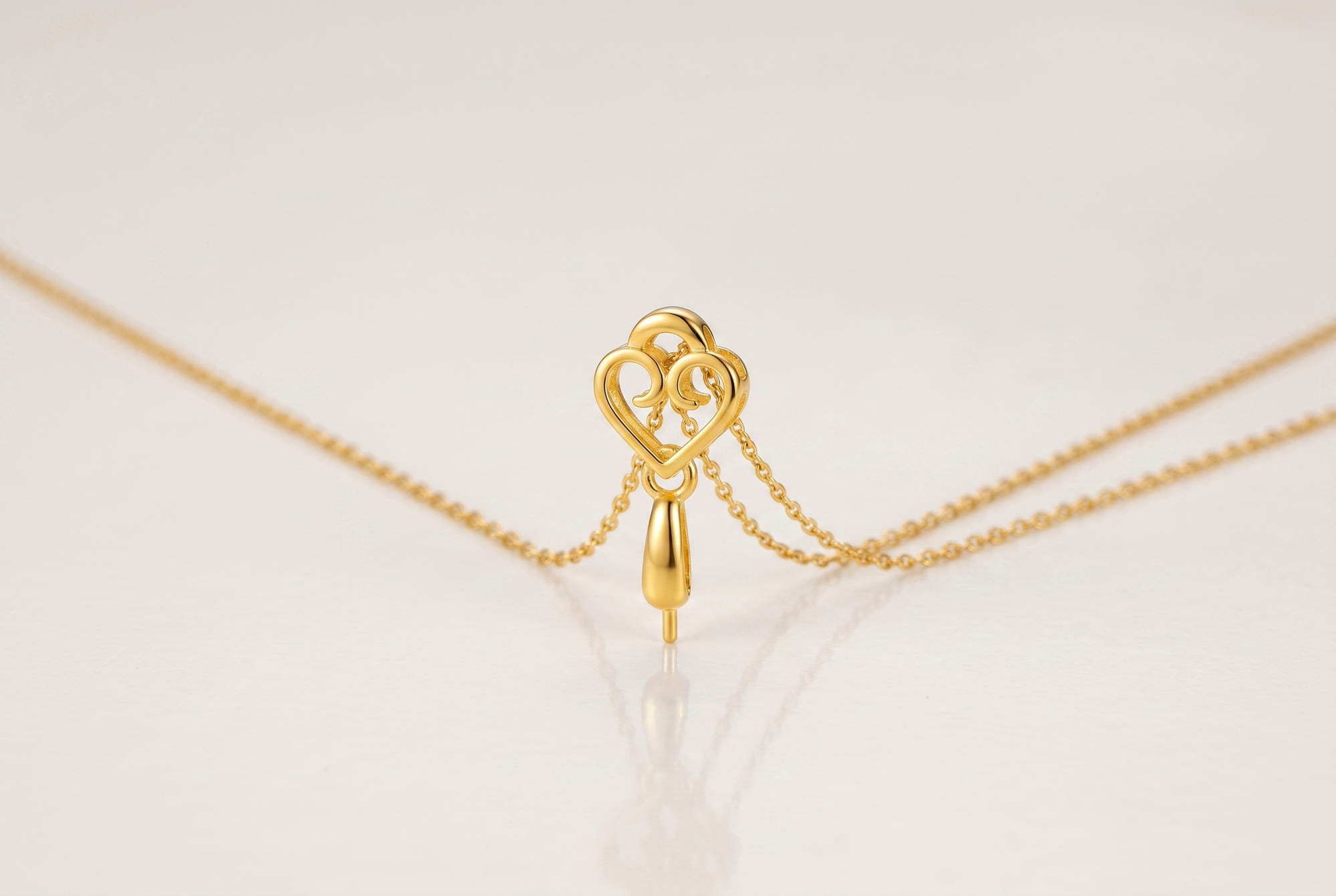 Gold-tone heart finding joining a pendant to a fine chain so it hangs straight