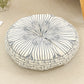Round cushion with a navy line sunburst print on a cream top and a navy patterned side, on a beige rug
