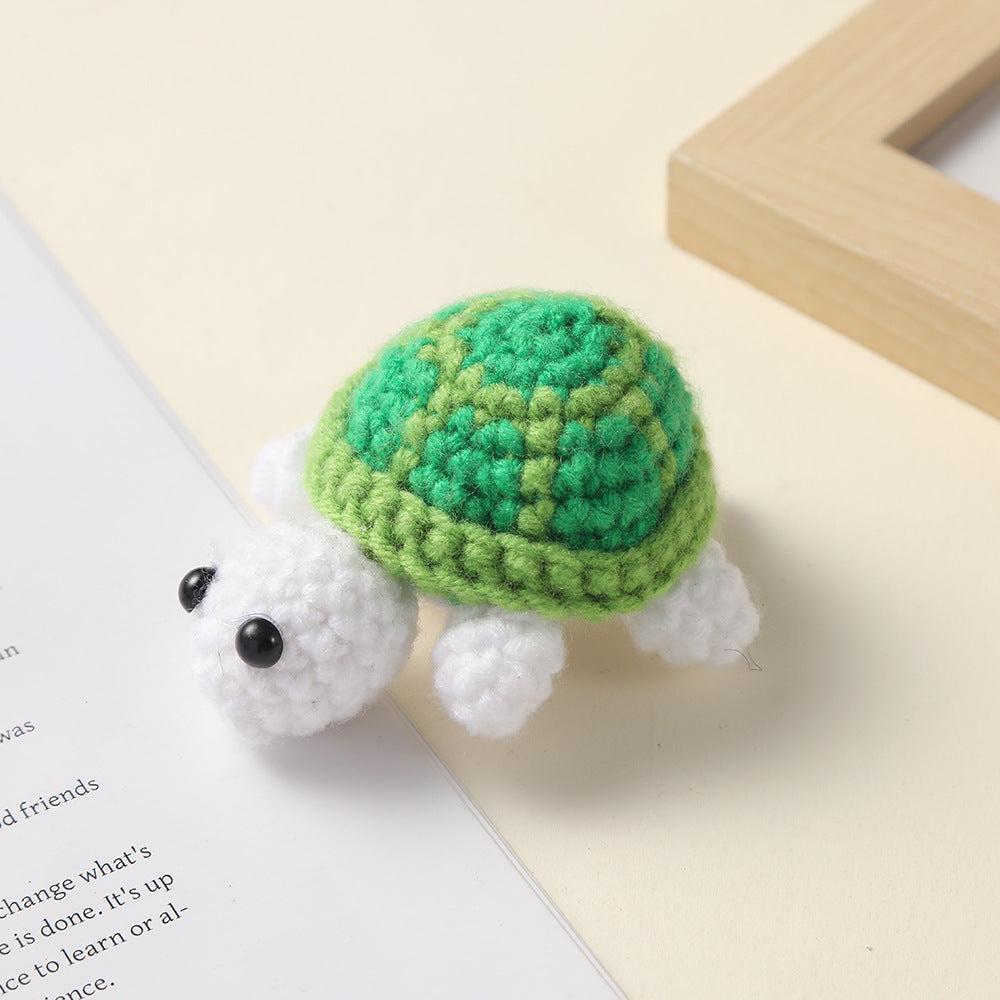 Crocheted light green shell white turtle, handmade wool charm on a cream surface