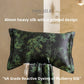 Dark charcoal silk pillowcase printed with green leaves, with matching printed silk fabric draped below it