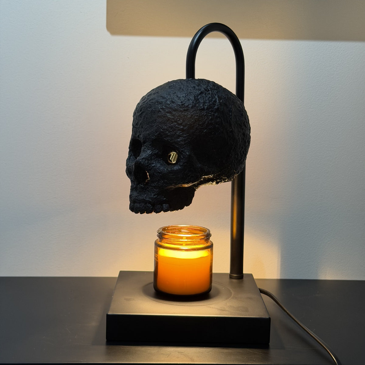 Fanged skull version of the candle warmer lamp on its curved metal arm and base