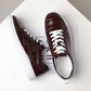 Burgundy sneakers seen from above and from the side with white laces, white insole and a tongue label