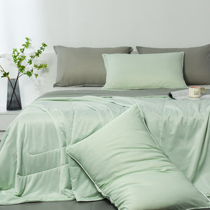 Pale green summer coverlet spread across a made bed with grey and green pillows behind