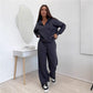 Dark gray zip front hooded sweatshirt and wide leg trousers set worn by a model with a mirror behind her