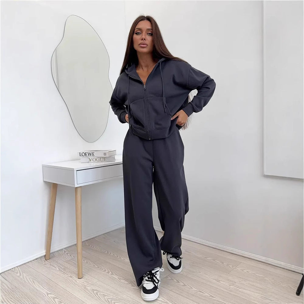 Dark gray zip front hooded sweatshirt and wide leg trousers set worn by a model with a mirror behind her