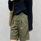 Woman wearing high-waisted olive Bermuda shorts with front pleats and relaxed straight legs