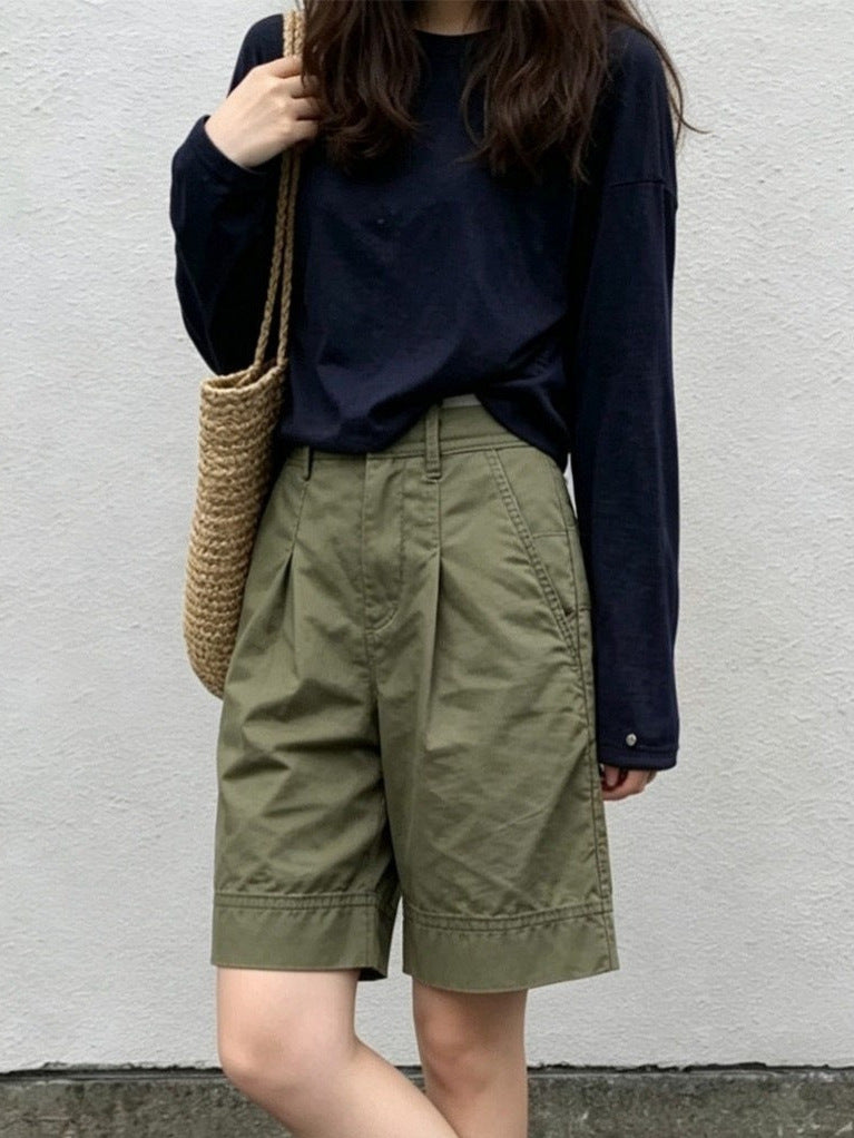 Woman wearing high-waisted olive Bermuda shorts with front pleats and relaxed straight legs