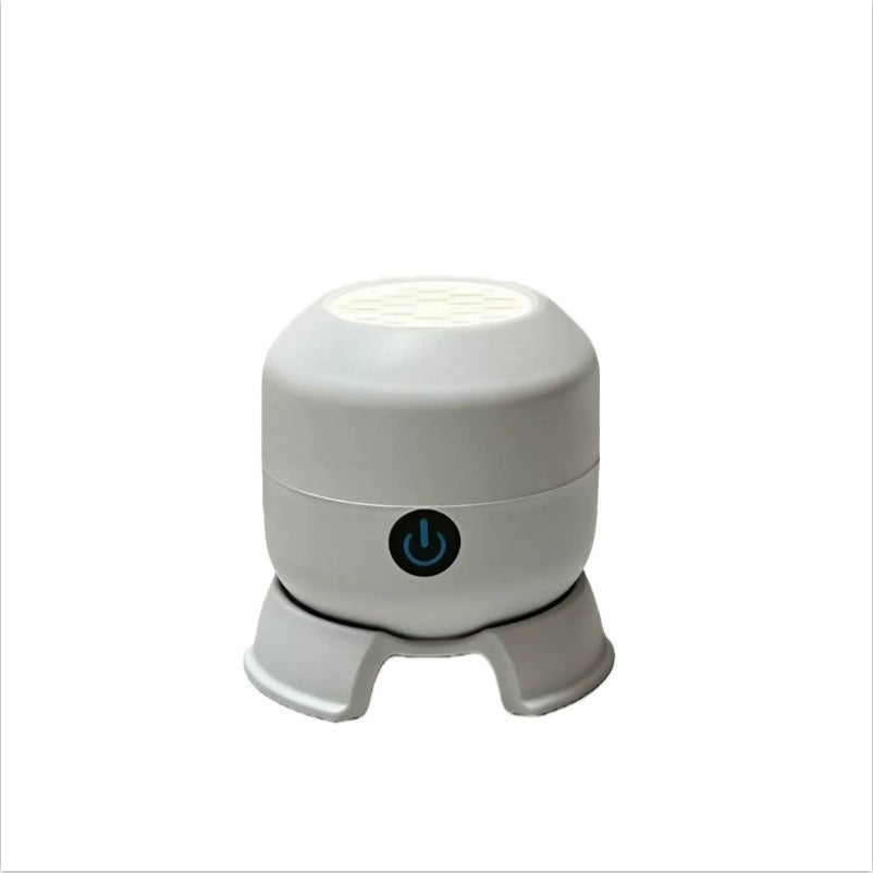 White cylindrical rotating projector night light with a power button on a three footed base, front view