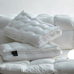 White quilted cotton sateen bed pillow with mesh gusset stacked on a bed