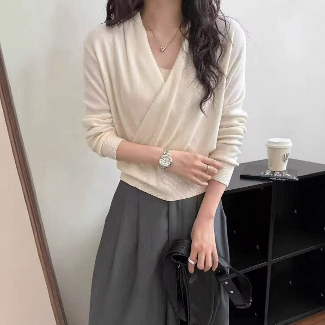 White knit sweater beside black on a hanger, showing the crossover front construction