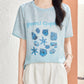 Woman in Lake Blue silk blouse with woven seashell and starfish motif on the chest